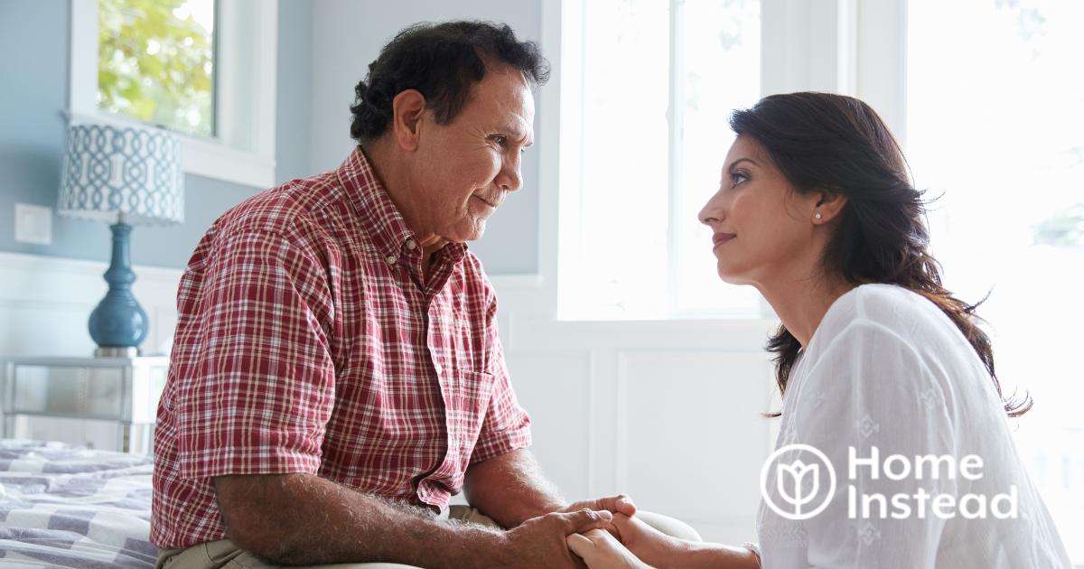 A daughter who is caregiving for her dad who has Alzheimer’s disease, lovingly holds his hands.