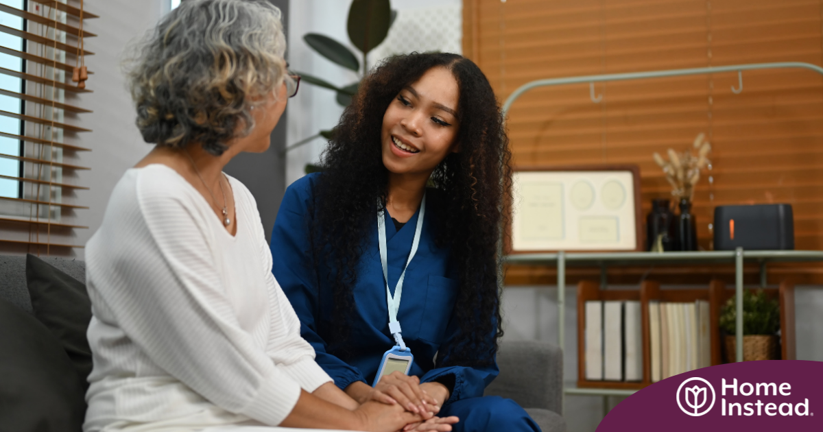 A caregiver patiently and kindly sits down and talks with a senior client, setting a good example for caregivers when it comes to communication.