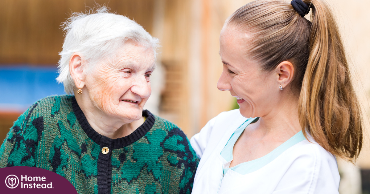 A professional caregiver compassionately hugs a senior client.