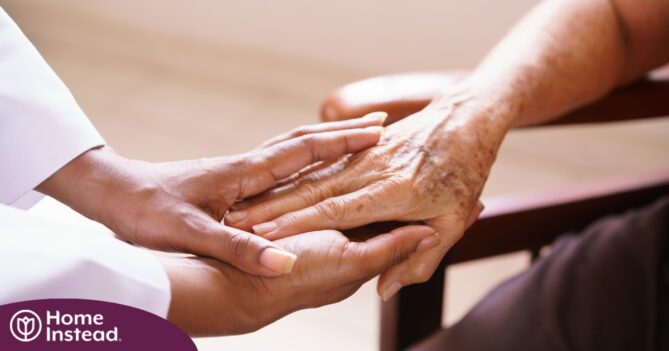 A pair of younger hands hold older ones, representing the compassionate care that a professional caregiver can provide.